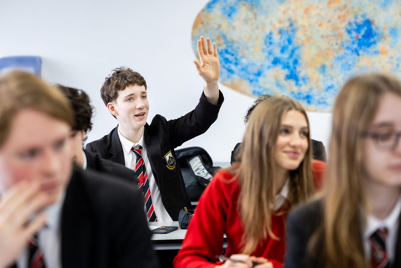 Professional education photography and student puts his hand up during a science lesson at Alexandra Park School in North London